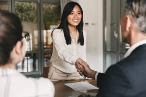 young woman shaking hand with business man at job interview