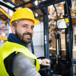 forklift operator man in yellow hard hat in factory warehouse